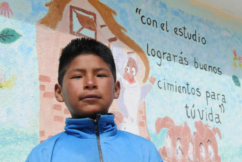 "Durch das lernen baust Du ein gutes Fundament für Dein Leben", steht auf der Schulmauer hinter Roberto | © UNICEF/ NYHQ2014-0498